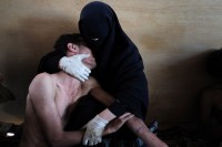 Fatima al-Qaws wiegt am 15. Oktober in Sanaa, Jemen, ihren Sohn Zayed (18) in den Armen. Er war von Tränengas getroffen worden, als er an einer Demonstration teilnahm. Anhaltende Proteste gegen das 33 Jahre andauernde Regime des autoritären Präsidenten Ali Abdullah Saleh eskalierten später an diesem Tag. Zeugen berichteten, dass Tausende über die Zubairy Straße, eine Hauptverkehrsstraße, gelaufen seien, und dass auf sie geschossen wurde, als sie den Regierungs-Checkpoint am Außenministerium erreichten. Einige Demonstranten wichen zurück, andere gingen weiter und wurden wieder beschossen. Es starben mindestens zwölf Menschen und etwa 30 wurden verletzt. Frau al-Qaws—selbst am Widerstand gegen das Regime beteiligt—fand ihren Sohn erst bei ihrer zweiten Suche unter den Verwundeten in einer Moschee, die als Feldlazarett genutzt wurde. Zayed war nach dem Zwischenfall zwei Tage im Koma. Er wurde bei weiteren Demonstrationen noch zweimal verletzt. Am 23. November floh Präsident Saleh nach Saudi-Arabien und unterzeichnete eine Vereinbarung, in der er die Macht seinem Stellvertreter Abdurabu Mansur Hadi übertrug. Salehs Herrschaft endete formell nach der Präsidentschaftswahl mit Hadis Vereidigung als Präsident am 25. Februar 2012. © Samuel Aranda, Spain, The New York Times